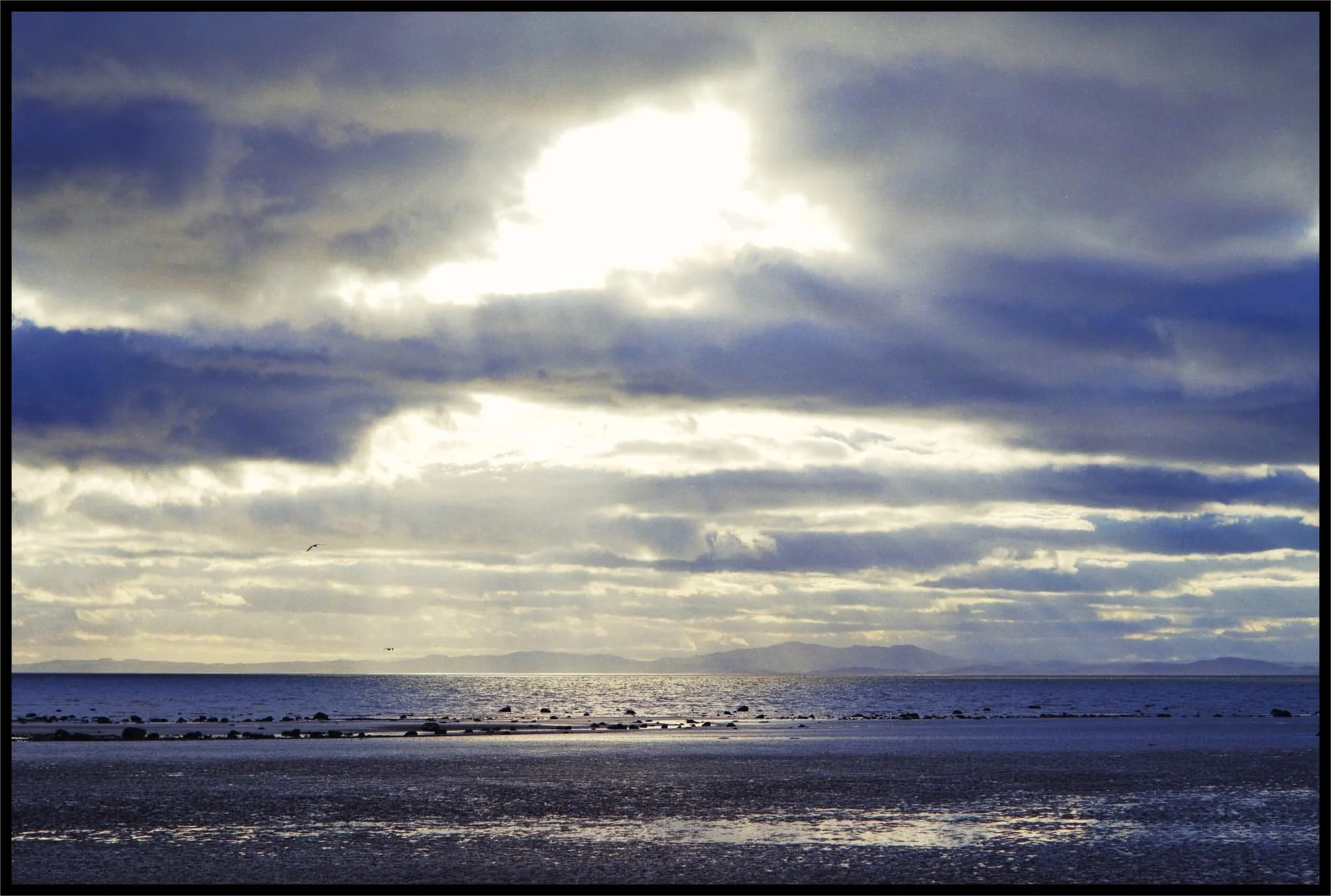 Crepuscular rays emerge from the heavens and cast golden light on the sea. 