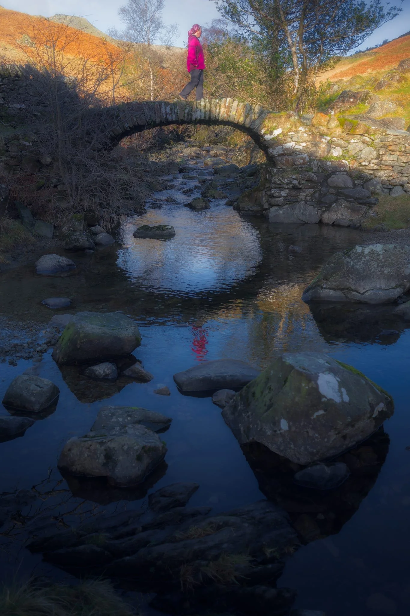  The old packhorse bridge itself, with my Lisabet providing a nice colour contrast as she strolls across it. As I&rsquo;ve mentioned on this site elsewhere, the name &ldquo;High Sweden Bridge&rdquo; might seem unusual, given this is located in the Lake District, England. The &ldquo;sweden&rdquo; aspect originally comes from the Old Norse  sviðin  (pronounced &ldquo;swee-thin&rdquo;), the past participle of  svíða , meaning &ldquo;to burn&rdquo; or &ldquo;to singe&rdquo;. In this context, it refers to the clearing of land by burning. 