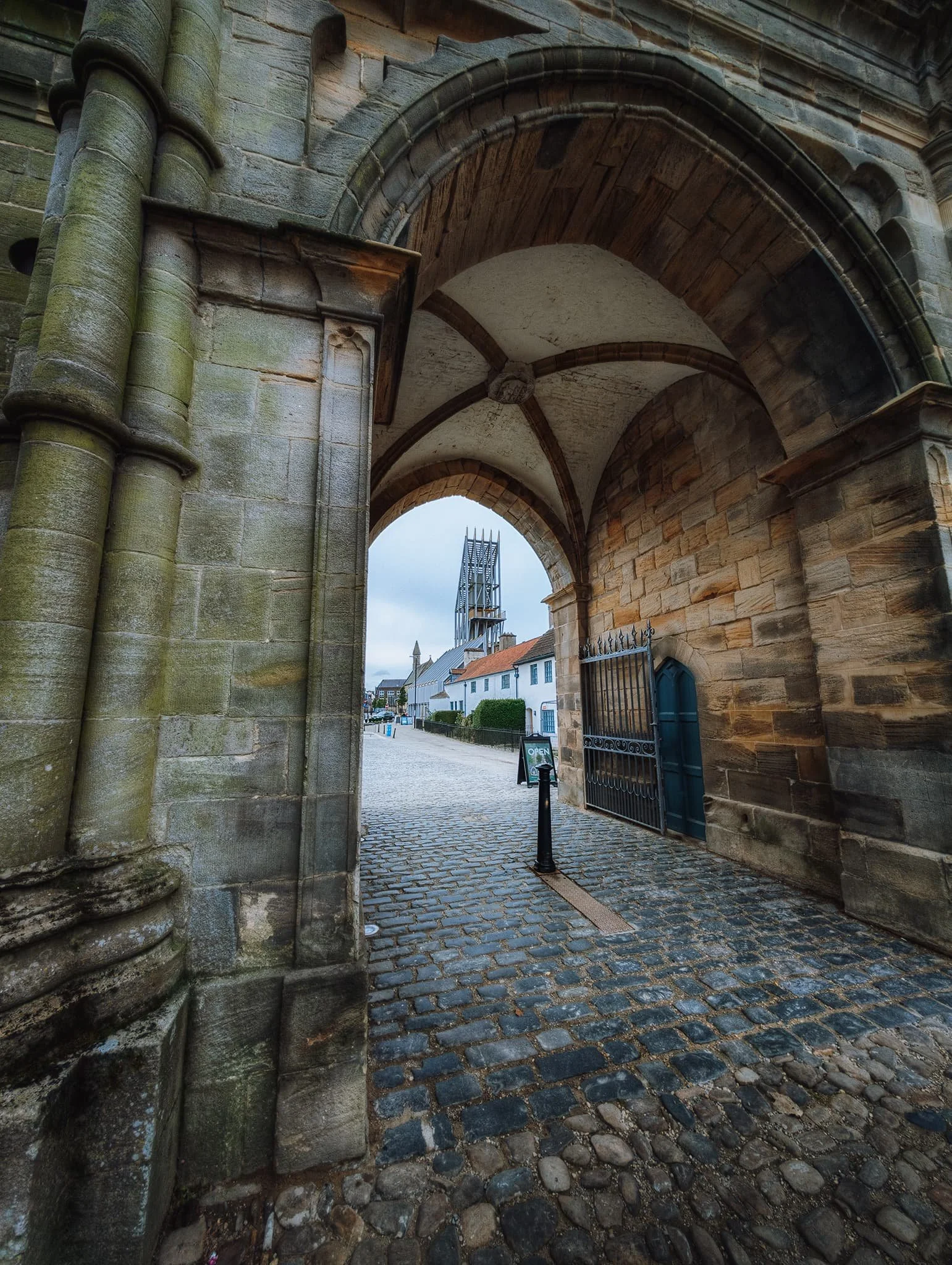  The castle gateway, using the archway as a frame for Auckland Tower in the distance. The gateway was built in 1760 by Sir Thomas Robinson of Rokeby for Bishop William Trevor. By contrast, Auckland Tower was built in 2017. The form of the tower is intended to echo lightweight provisional structures that would&rsquo;ve been used by invaders to breach castle walls. 