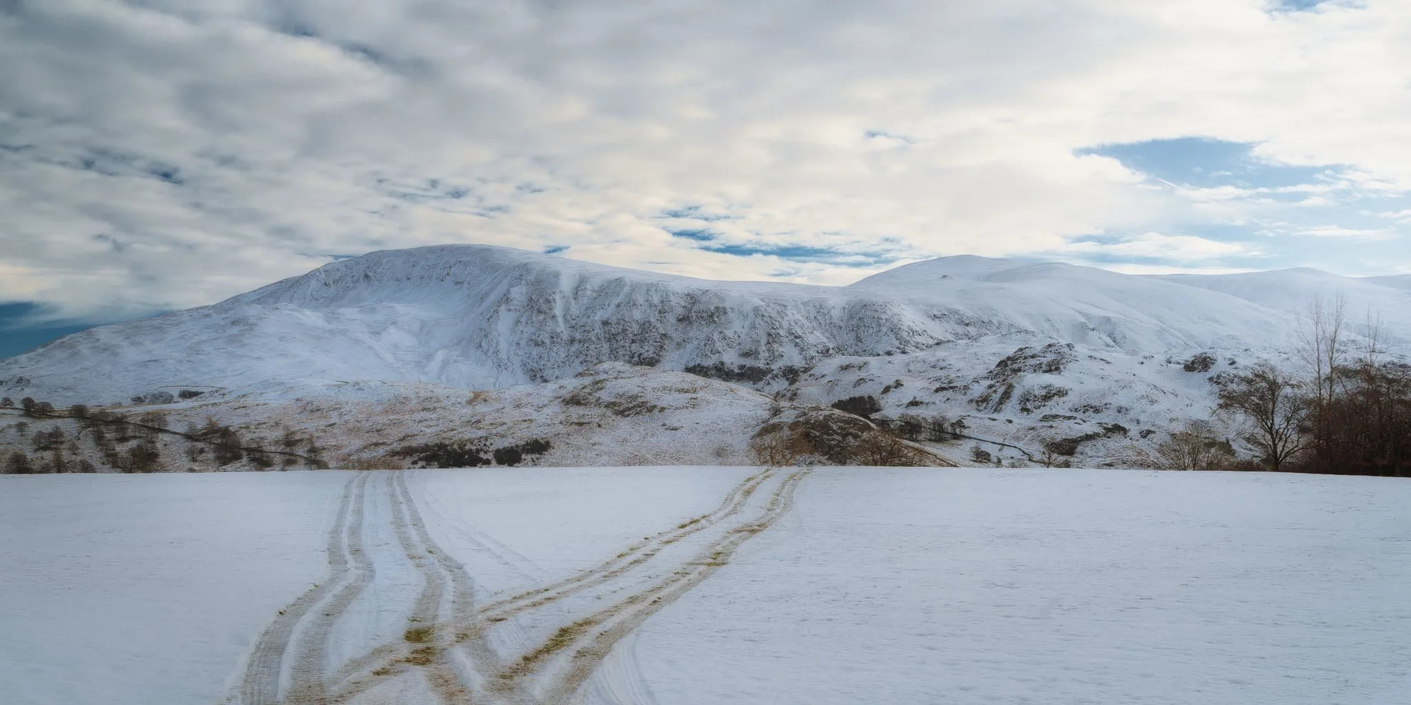  Across the fields eastwards, the end of Helvellyn range at Great Rigg provides a beautiful panorama. A farmer&rsquo;s quad tracks provide a handy compositional leading line. 