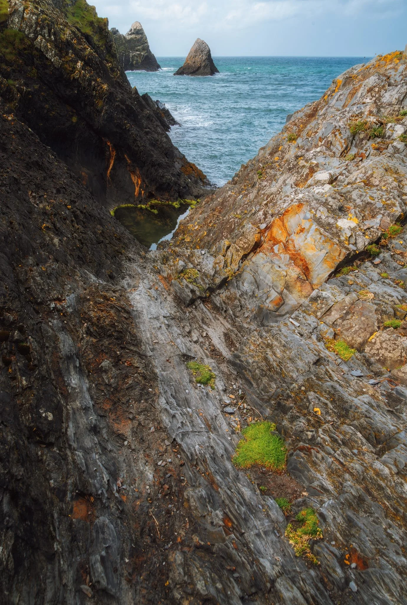  Gingerly navigating the ankle-breaking fins and folds, I edged closer to the cliff face. This wonderfully deep fold in the rocks gave me another composition to explore with the two sea stacks. 