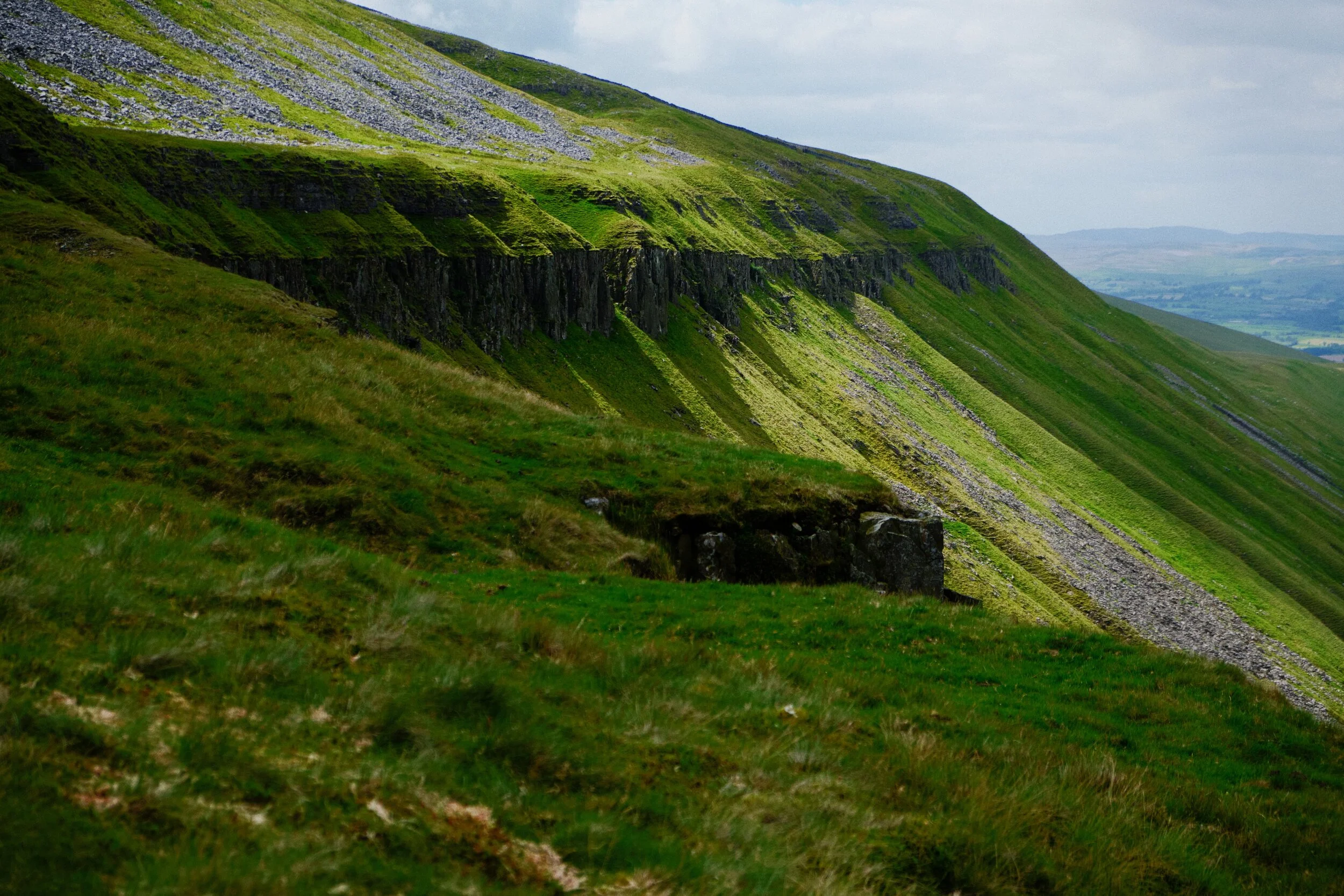  Streams of lights pour through the various gills in between numerous breaks within the Whin Sill cliff. 
