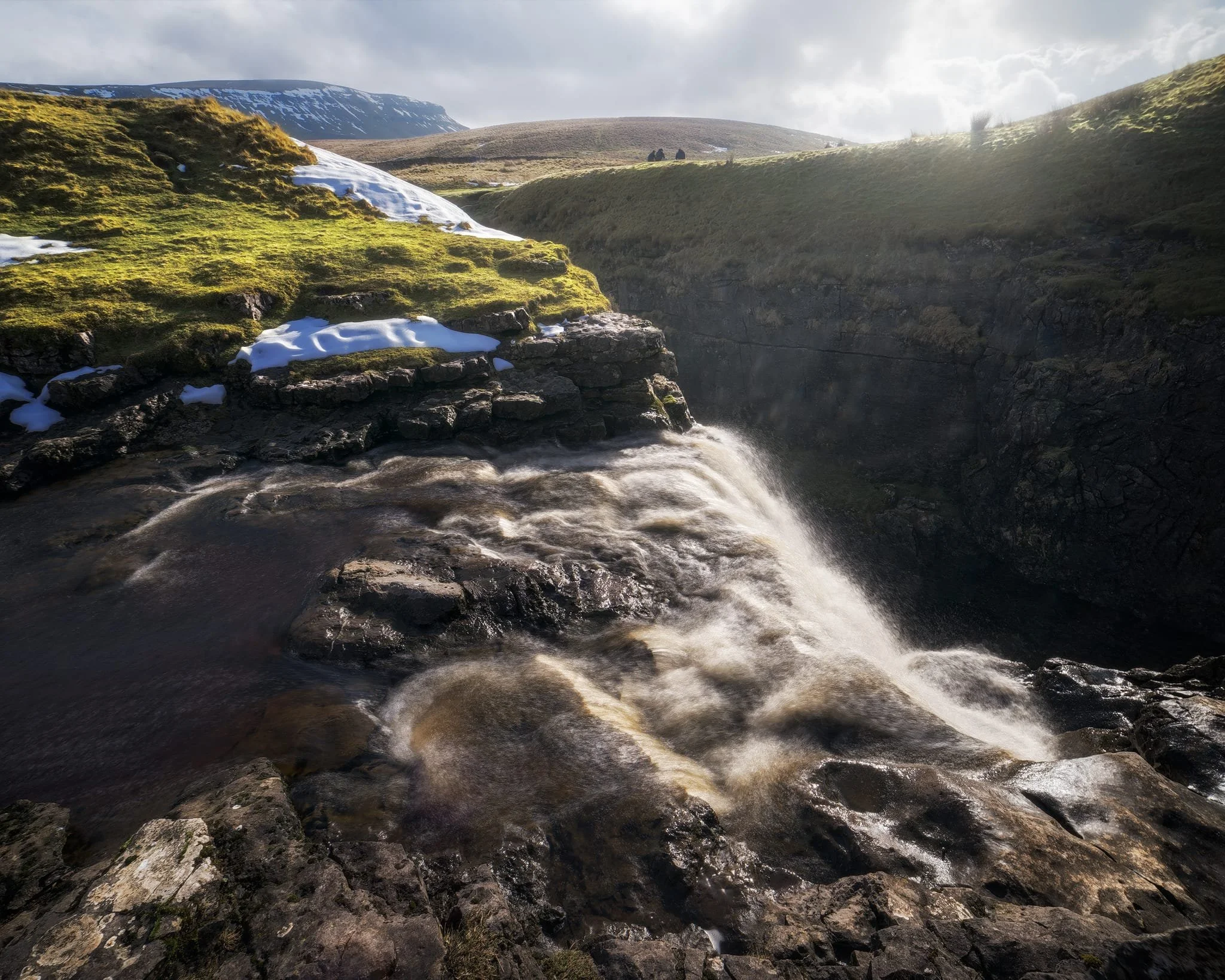  We clambered as close to the waterfall as possible as it crashed over the edge into Hull Pot. As I had no tripod, I shot this with my ultra-wide 14mm at f/22, taking multiple exposures of the same scene. In post, I then averaged the exposures together that gave me that long exposure effect on the water.  