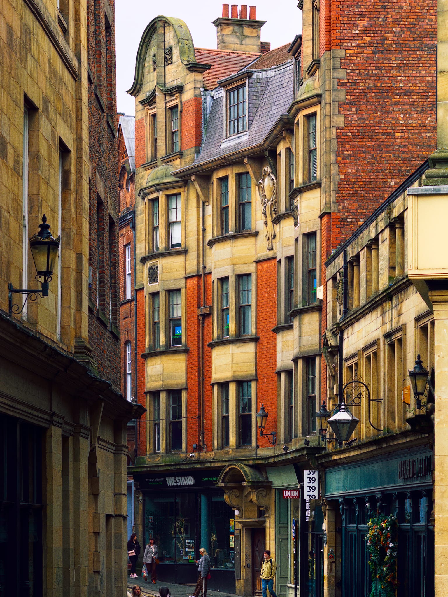 The western area of High Bridge, featuring prominent red brick and stone detailing in the buildings. The street was called such because of the bridge that once spanned the Lort Burn, which is now underground.