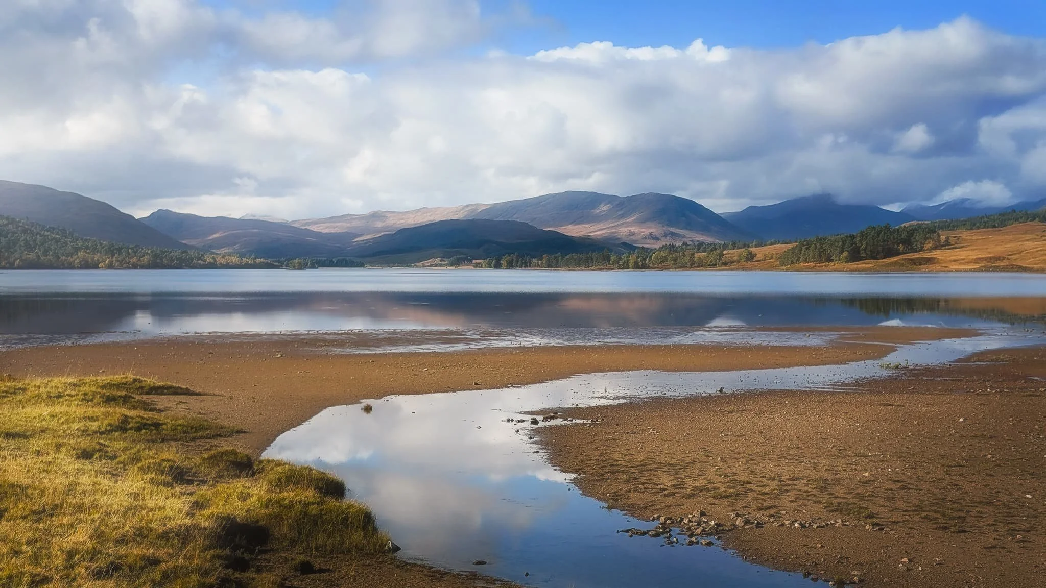  It turns out that getting to the loch shore of  Loch Tulla  is difficult. The road runs right alongside its north-eastern point, and is raised above the loch. You can&rsquo;t clamber down the verge towards the shore because of barbed fencing. So, this shot from the roadside of Tulla and towards the Black Mount range was as best as I could manage.  