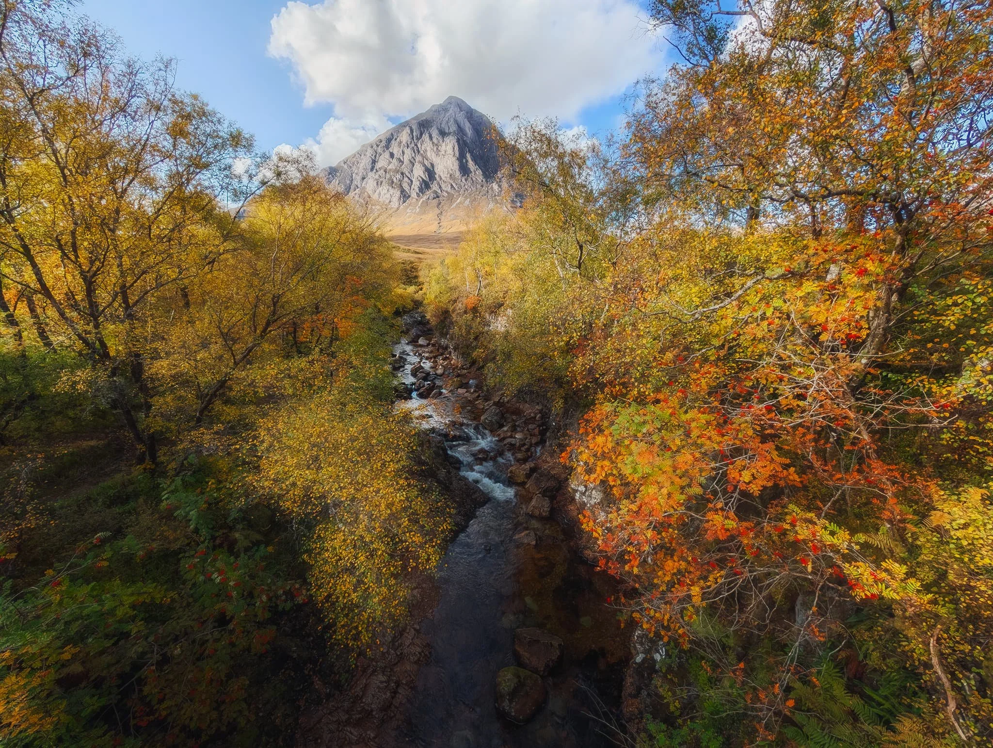  Beyond Rannoch Moor and the myriad of lochs, we stopped at an unmissable place on the way towards Glencoe. This is the River Coupall, which has gouged out a gorge lined with incredible autumn foliage. In the distance is the impossibly perfect peak of  Buachaille Etive Mòr  (1,021.4 m/3,351 ft). 