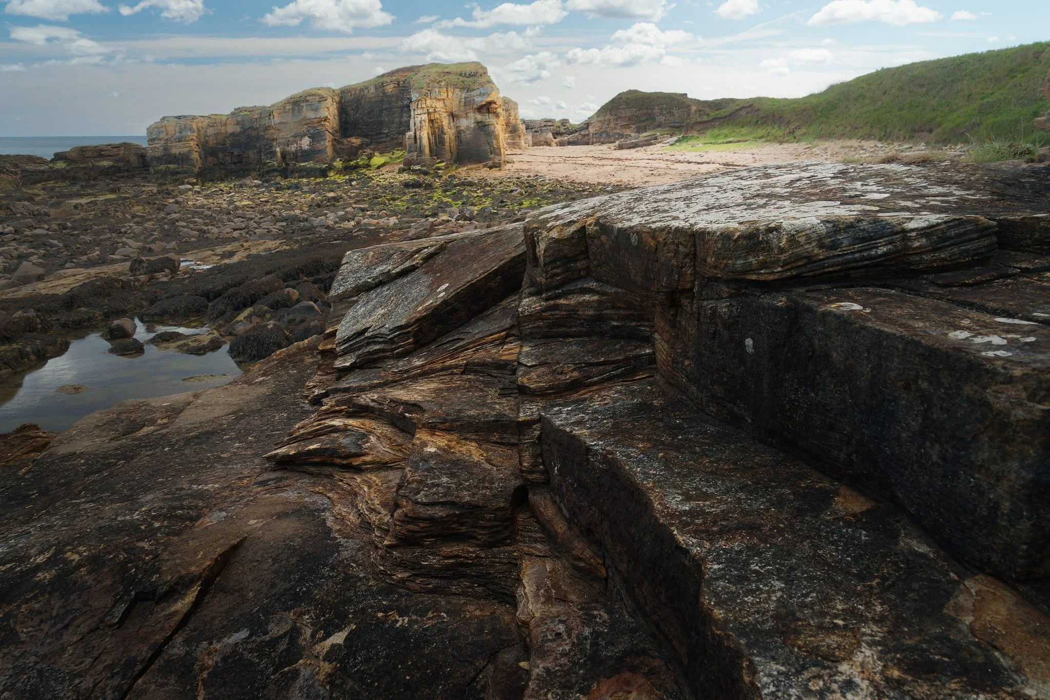  We did  not  expect to see what we found when we decided to have a nosey around the Rumbling Kerns of Howick.  Wow . The geology around here is crazy. The dark, thin layers in the foreground are old floodplain muds and silts, deposited when the river overflowed its banks and settled out fine particles. The chunky, blocky sandstones you see further back are the main river channels (the Rumbling Kern) where fast water dumped coarser sand. Over time, ice-age floods and tides have smoothed and sculpted both. 