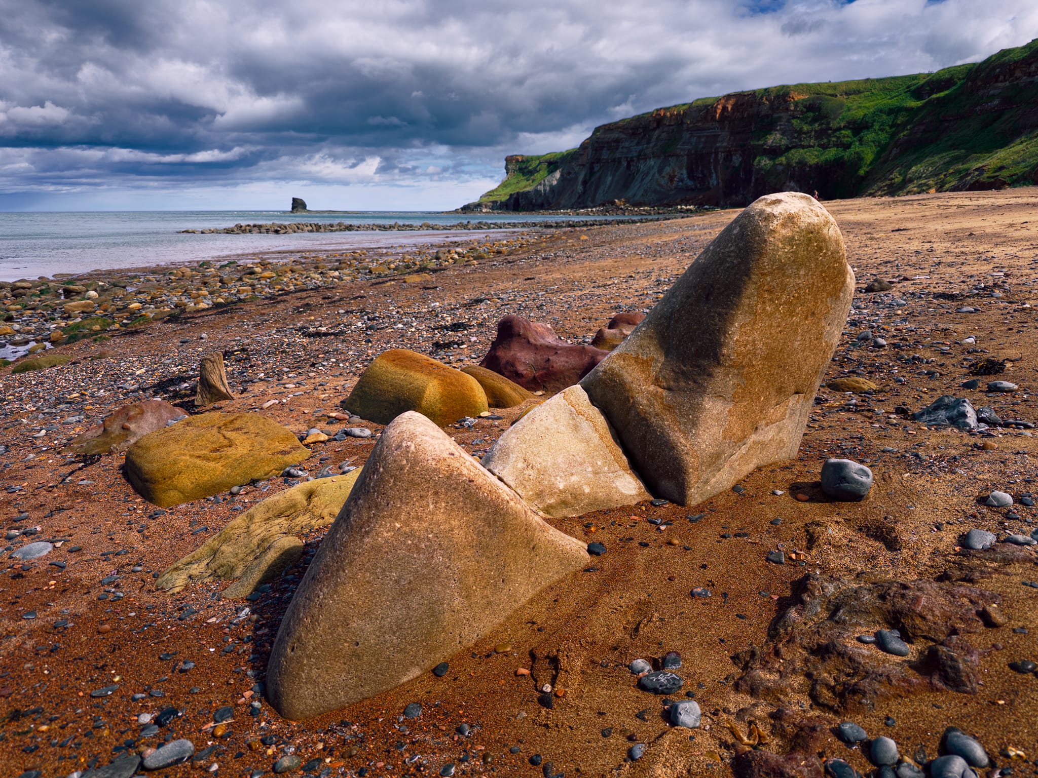 This little group fascinated me. These are sandstone blocks, fallen from the cliff and then tilted upright by wave action digging sand from underneath as the tide moves them. The wedge shapes come from the rock’s natural jointing, they fracture along those planes when they break off the cliff face.