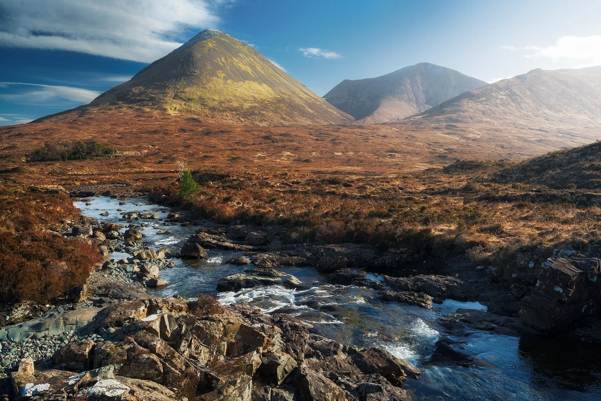  Looking back down the river towards the Red Cuillins saw clearer skies. On the left, the wizard&rsquo;s hat of a mountain is  Glamaig  (775 m/2,543 ft), catching the light on its smooth flanks. The other Red Cuillin in the distance is  Beinn Dearg Mhòr  (731 m/2,398 ft) 