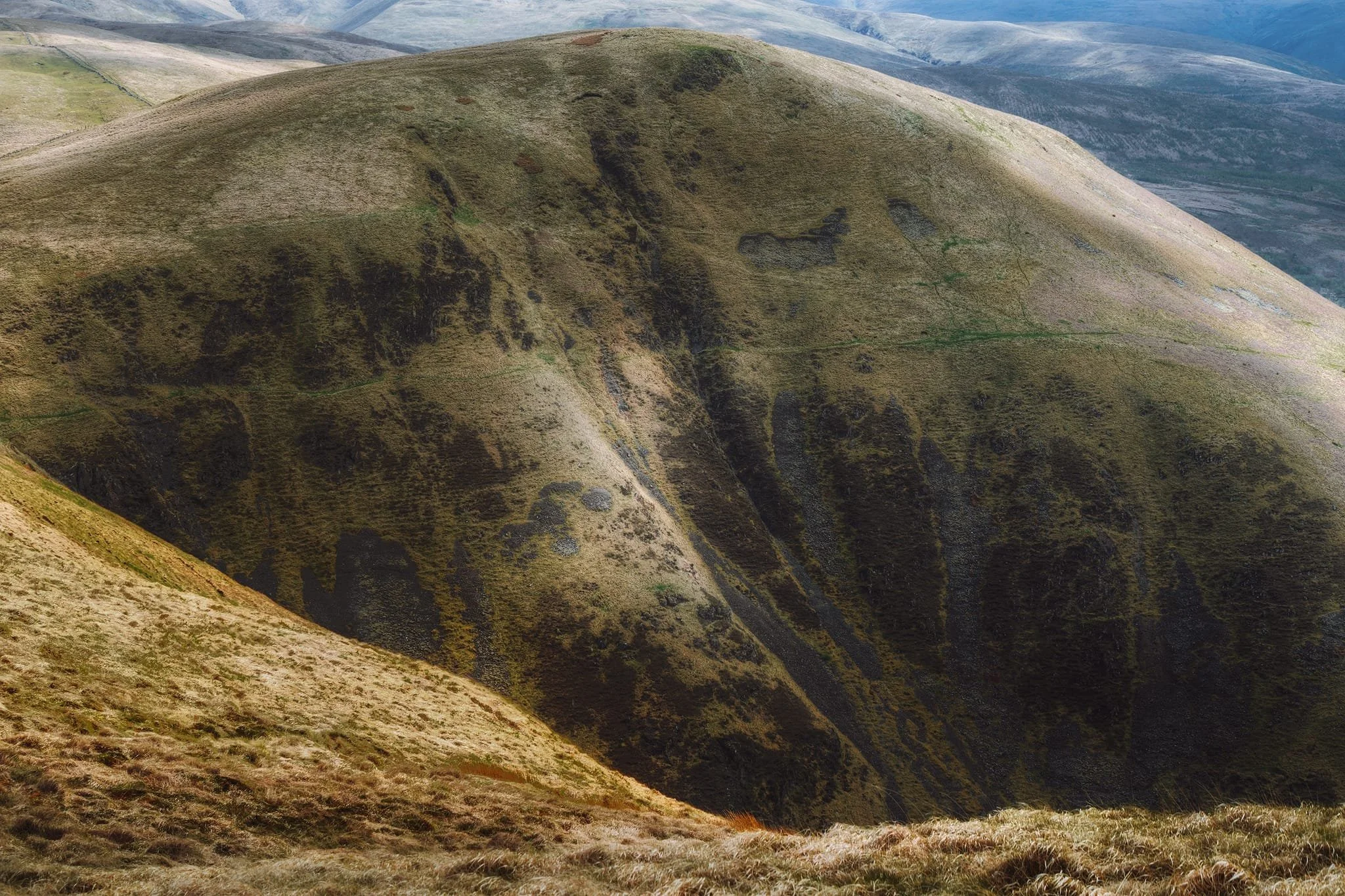  I couldn&rsquo;t resist zooming in on the impressively steep and scarred western face of Great Hill, as the light gently scanned across its features. Summitting Great Hill was our next goal but even in dry conditions the path up to its peak was a veritable quagmire so we backed off and head back. Maybe another time. 