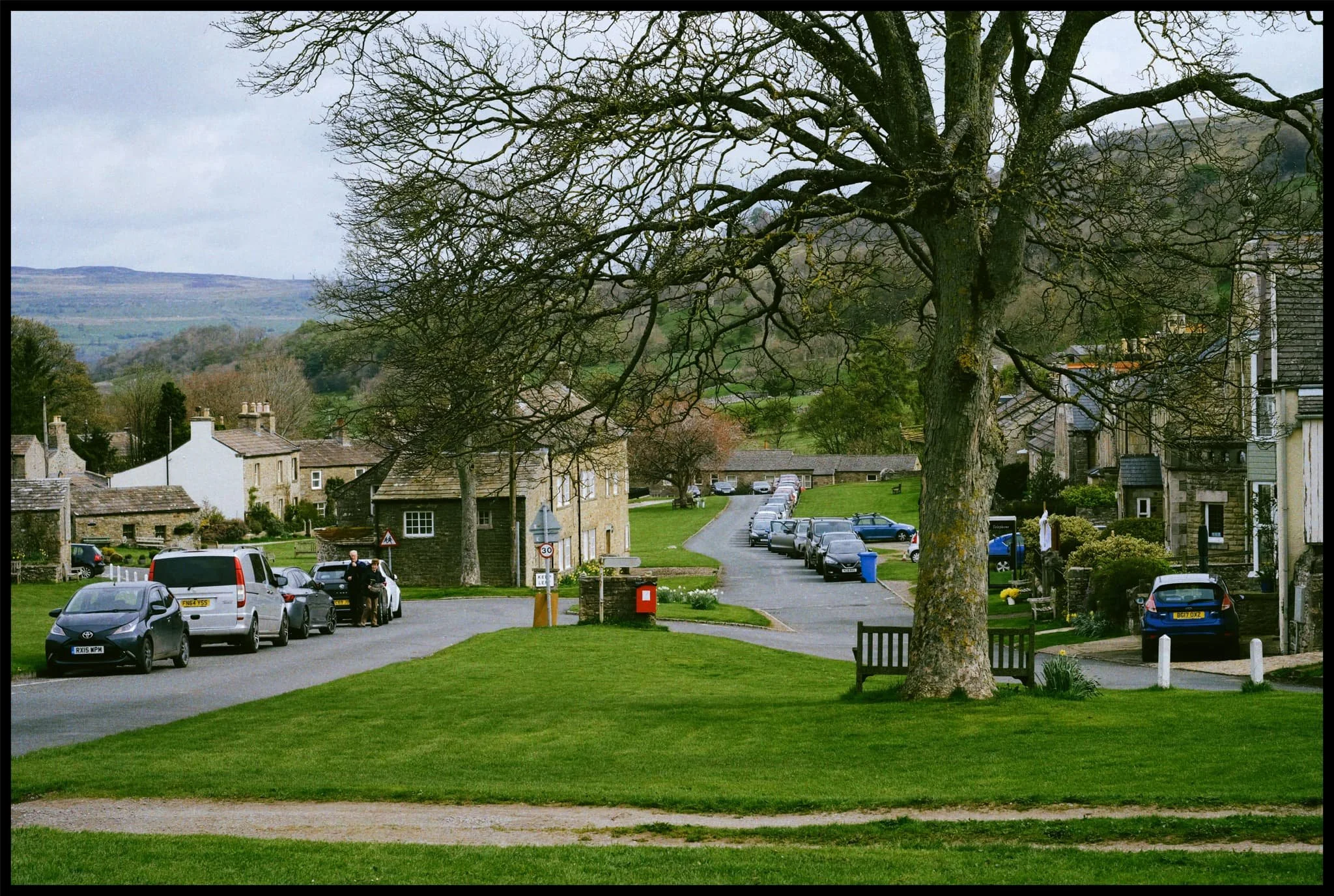  The beautifully manicured village green runs alongside the Main Street through the village. In the distance are the Wensleydale fells. 